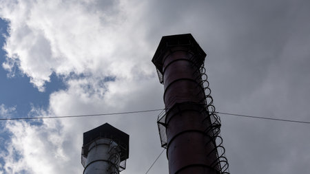 Smokestack of an industrial plant against a blue sky with clouds