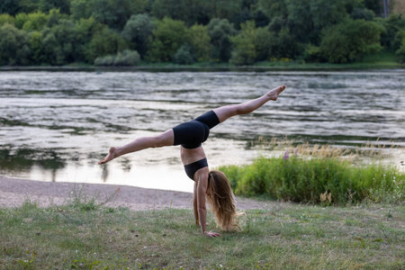 Beautiful young woman doing yoga exercise in nature by the river