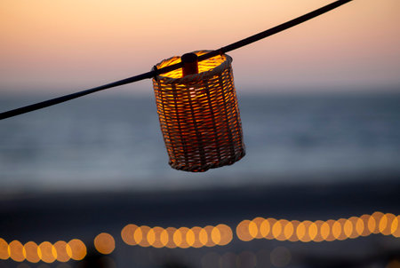 A lamp hangs on a wire against the background of a beach sunset.の写真素材