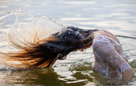 Young pretty girl relaxing bath in lake before golden sunset