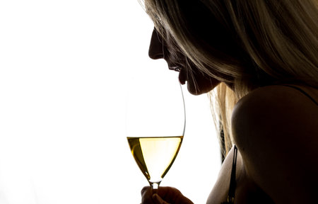 Woman drinking white wine, silhouette with glassの写真素材