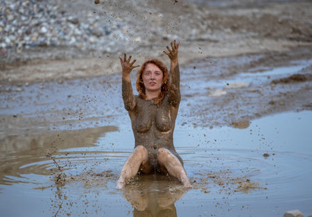A woman expresses her emotions in a muddy puddle
