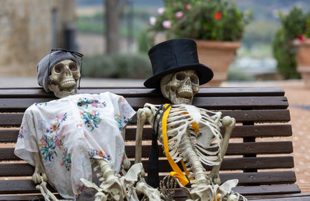 Scary skeletons sit on a bench, an outdoor Halloween decoration, in the Italian town of Solomeoの写真素材