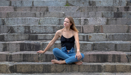 Fashionable beautiful woman on the steps of a summer dayの写真素材