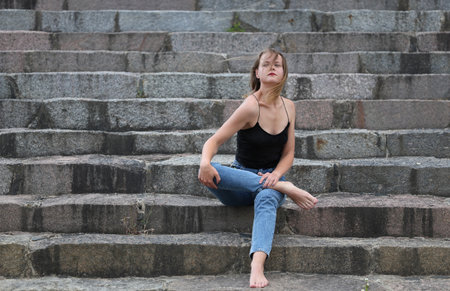 Fashionable beautiful woman on the steps of a summer dayの写真素材