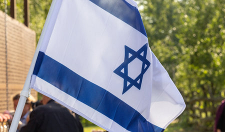 The National Flag of Israel Fluttering in the Breeze Against a Background of Treesの写真素材