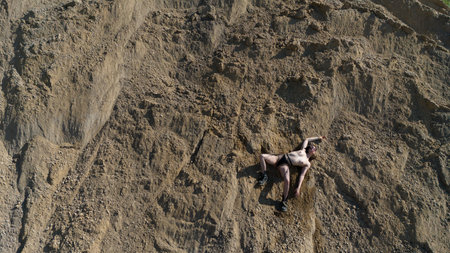 Woman with holey legs and round glasses posing in a gravel pitの写真素材