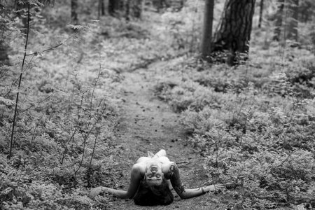 A beautiful, bold dark-haired girl. Posing while lying on a forest trackの写真素材