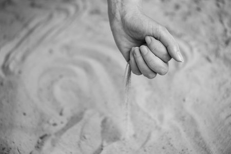 Time Slipping Through Fingers in Grains of Sand. A Moment Slipping Along with Streams of Sandの写真素材