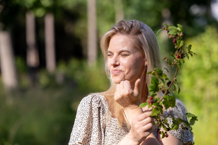 Young beautiful woman eating wild raspberries in the forestの写真素材