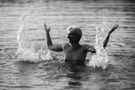 Happy woman in the sunset, splashing in the lake, warm autumn eveningの写真素材