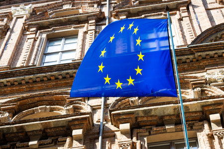 European Union flag waving above the city, blue with a yellow star