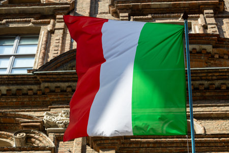 Italian flag waving above city buildings, red, white, green