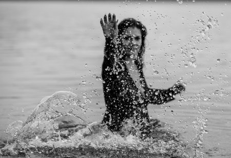 Woman in Black Attire Splashing in Water: Elegance Meets Natureの写真素材