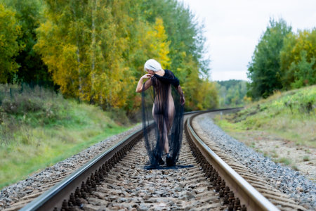 Female figure from behind, draped in tulle, on railway tracksの写真素材