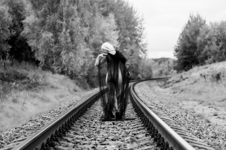Female figure from behind, draped in tulle, on railway tracksの写真素材