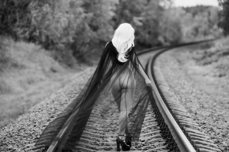 Female figure from behind, draped in tulle, on railway tracksの写真素材