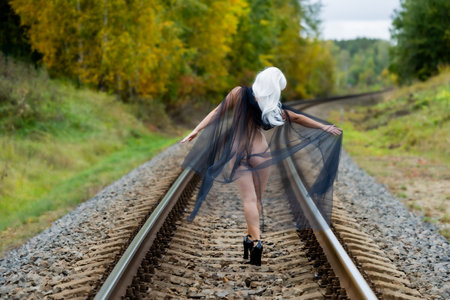 Female figure from behind, draped in tulle, on railway tracksの写真素材