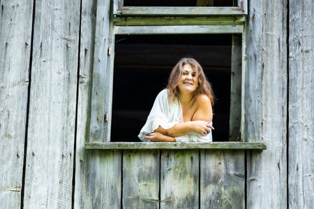 Modern Elegance in a Historic Window: A Woman Posing in an Old House, Surrounded by Memoriesの写真素材