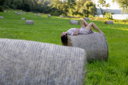 A beautiful woman surrounded by nature, posing on hay balesの写真素材