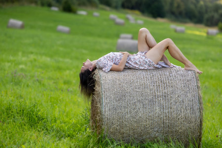 A beautiful woman surrounded by nature, posing on hay bales