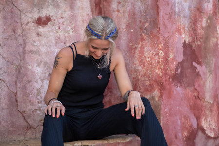 A beautiful woman sitting by an old pink wall