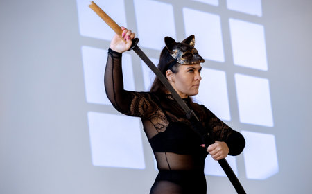 A woman wearing a Warrior Cat mask and holding a sword enjoys posing