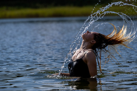 Energetic Hair Flip and Sparkling Water Splash â Beautiful Woman Enjoying a Summer Day in Natureの写真素材