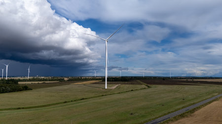 A modern wind turbine stands tall against a dark and cloudy stormy sky. Renewable energy symbolizing...