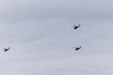 A formation of three military helicopters flies across the cloudy sky over Poland. A striking...