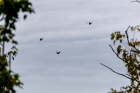 A formation of three military helicopters flies across the cloudy sky over Poland. A striking...