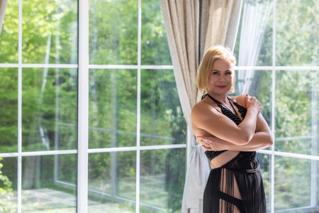 Sunlight paints her skin as she moves with elegance and strength. Surrounded by glass and nature, she embodies freedom, confidence and timeless feminine beauty in a serene, modern spaceの写真素材