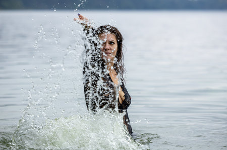 Woman in Black Attire Splashing in Water: Elegance Meets Natureの写真素材