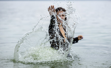Woman in Black Attire Splashing in Water: Elegance Meets Natureの写真素材
