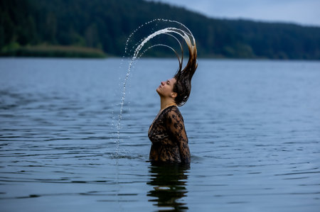 Charming hair arc with water droplets, woman in black blouse, vacationの写真素材