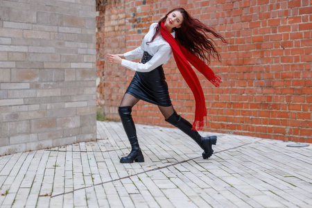 Dynamic portraits of a woman dancing in an urban alley with a brick wall background. Energetic movement, fashion details and expressive motion captured outdoors in natural lightの写真素材