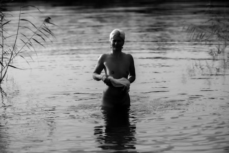Happy woman in the sunset, splashing in the lake, warm autumn eveningの写真素材