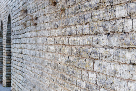 Historic stone wall with repeating vertical columns creating rhythm and depth. Natural masonry...