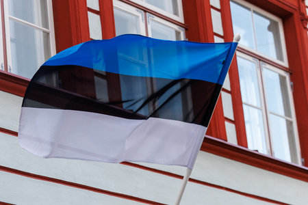 Blue, black and white national flag waving on a historic building in a European city. Symbol of national identity, independence and Baltic regional heritage in an urban architectural settingの写真素材
