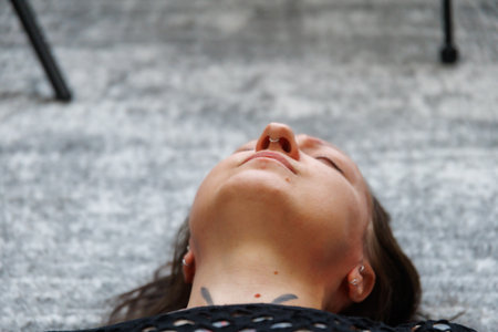 Young adult woman lying on the floor with closed eyes, expressing emotional release, vulnerability and calm. Concept of mental health, self care, body awareness, inner peace, therapy and mindfulness.の写真素材