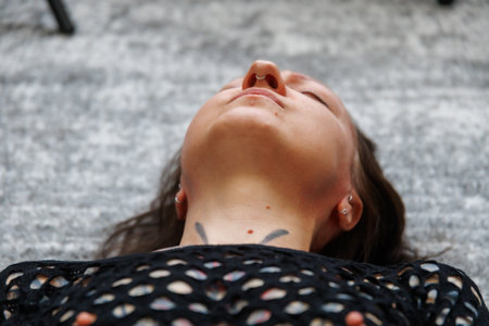Young adult woman lying on the floor with closed eyes, expressing emotional release, vulnerability and calm. Concept of mental health, self care, body awareness, inner peace, therapy and mindfulness.の写真素材