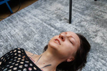 Young adult woman lying on the floor with closed eyes, expressing emotional release, vulnerability and calm. Concept of mental health, self care, body awareness, inner peace, therapy and mindfulness.の写真素材