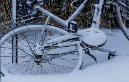 Snow covered bicycle parked outdoors in winter. Urban winter scene with cold weather, fresh snow and quiet atmosphere. Minimal composition with natural light and seasonal backgroundの写真素材