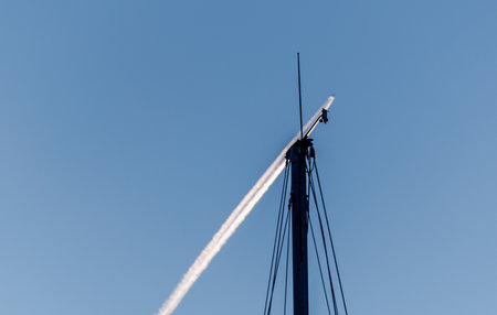 Minimal composition of an aircraft contrail crossing a clear blue sky with a small technical...