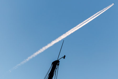 Minimal composition of an aircraft contrail crossing a clear blue sky with a small technical...