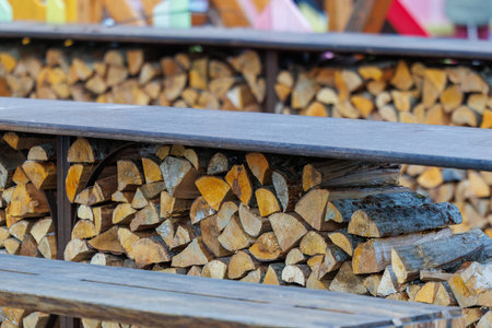 Close-up of neatly stacked chopped firewood stored under a wooden shelter, showing natural textures...