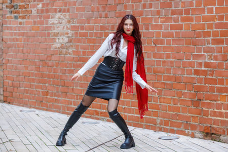 Dynamic portraits of a woman dancing in an urban alley with a brick wall background. Energetic movement, fashion details and expressive motion captured outdoors in natural lightの写真素材