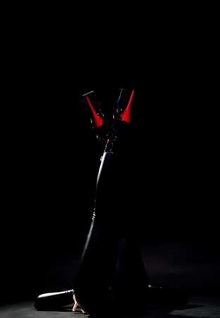 Stylish black high heel platform boots with red laces and heels photographed in dark studio. Fashion...