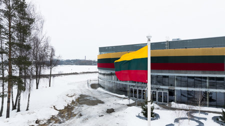 KEDAINIAI, LITHUANIA â FEBRUARY 27, 2026: Lithuanian national flag waving near Kedainiai Arena building decorated in national tricolor colors during winter seasonの写真素材