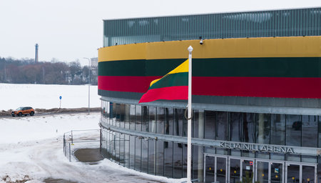 KEDAINIAI, LITHUANIA â FEBRUARY 27, 2026: Lithuanian national flag waving near Kedainiai Arena building decorated in national tricolor colors during winter seasonの写真素材